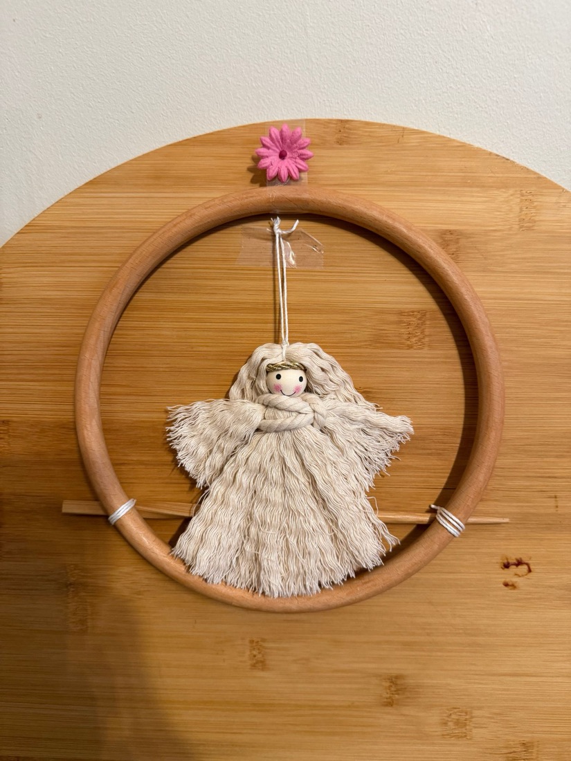 Cream macramé angel suspended inside a natural wood hoop